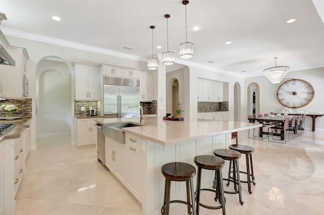 kitchen featuring arched walkways, a sink, stainless steel appliances, and tasteful backsplash