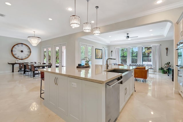kitchen featuring an island with sink, stainless steel dishwasher, a sink, visible vents, and open floor plan
