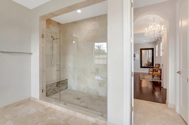 bathroom featuring a stall shower, tile patterned flooring, an inviting chandelier, and baseboards