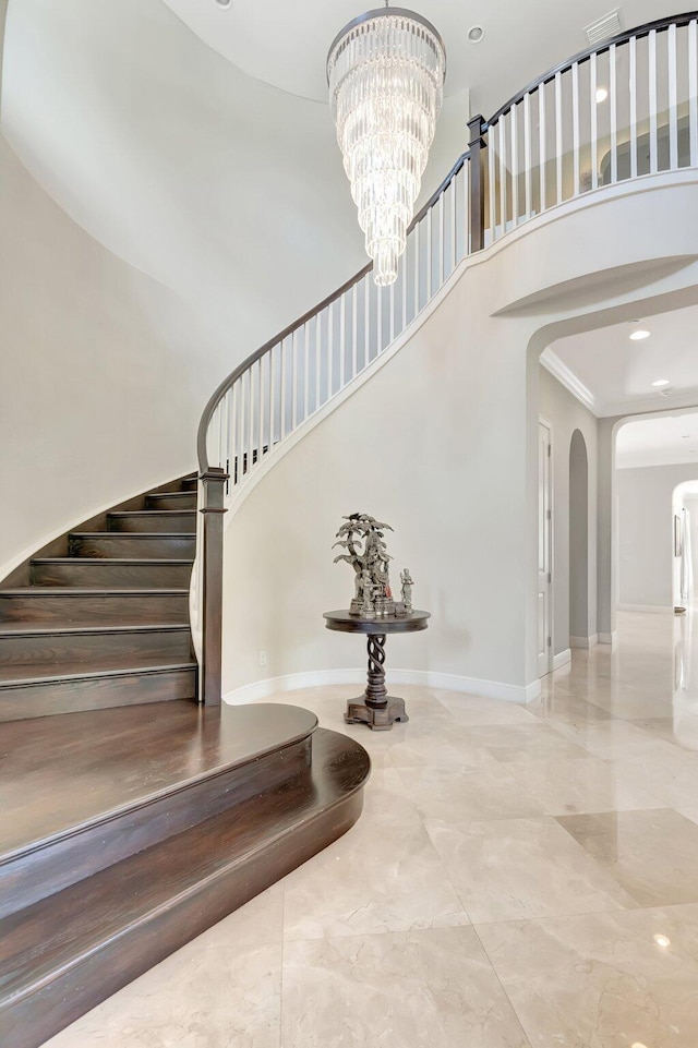 stairway featuring a notable chandelier, visible vents, arched walkways, and a high ceiling