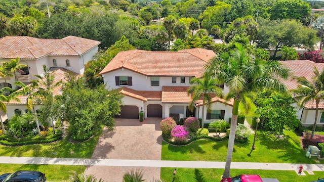 view of front facade with driveway, a tile roof, a front yard, an attached garage, and stucco siding