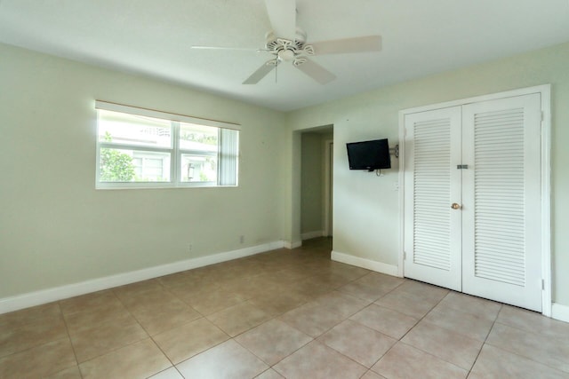 unfurnished bedroom with a closet, baseboards, ceiling fan, and light tile patterned floors