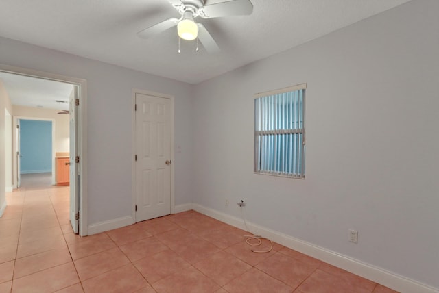 spare room with light tile patterned floors, baseboards, and ceiling fan