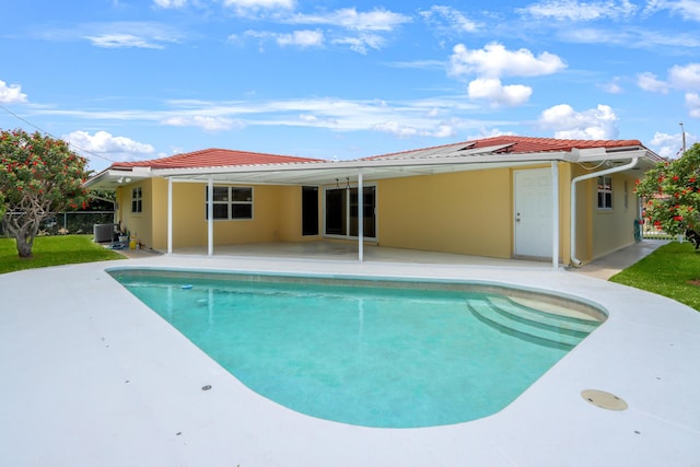 back of property featuring a patio, a tile roof, an outdoor pool, and central AC