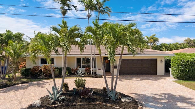 ranch-style home with an attached garage, decorative driveway, and stucco siding