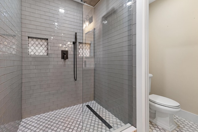 bathroom with baseboards, walk in shower, and toilet