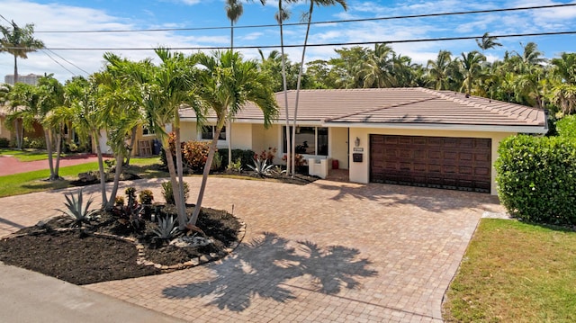 ranch-style house featuring an attached garage, stucco siding, and decorative driveway