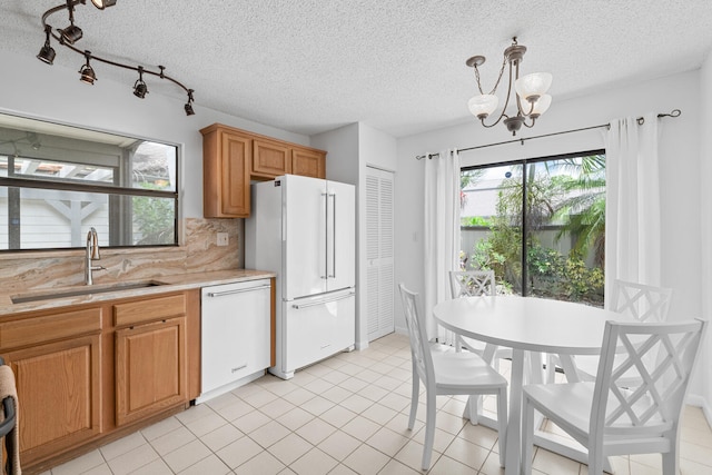 kitchen featuring a sink, decorative backsplash, white appliances, light countertops, and a textured ceiling