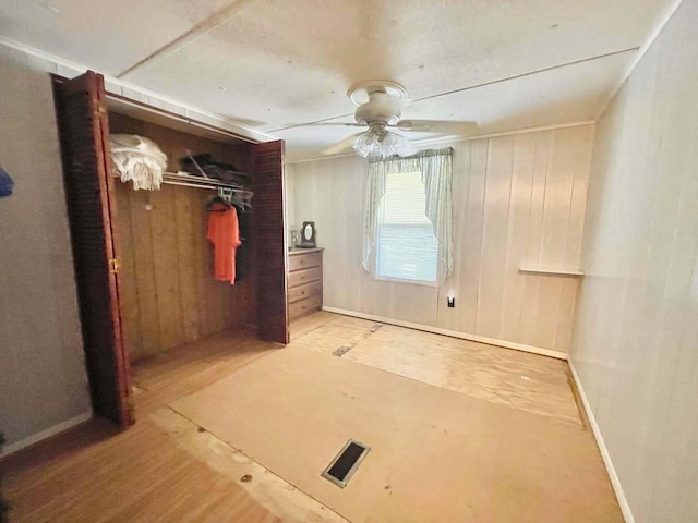 3020 SE 38th Ave, Okeechobee, FL 34974 - unfurnished bedroom featuring wood finished floors, a closet, wood walls, ceiling fan, and visible vents