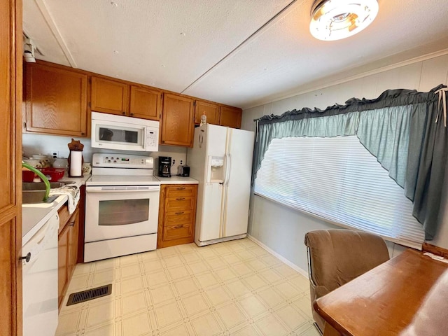 3020 SE 38th Ave, Okeechobee, FL 34974 - kitchen with white appliances, light floors, brown cabinetry, light countertops, and visible vents