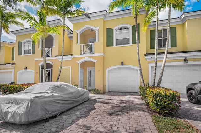 multi unit property featuring an attached garage, decorative driveway, and stucco siding