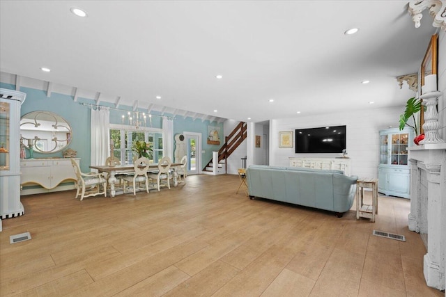 living room featuring stairway, light wood-type flooring, and visible vents