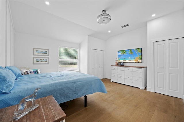 bedroom featuring two closets, recessed lighting, wood finished floors, and visible vents