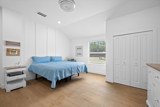 bedroom featuring baseboards, light wood-style flooring, lofted ceiling, and visible vents