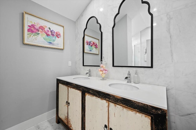 full bath featuring a sink, baseboards, double vanity, and marble finish floor