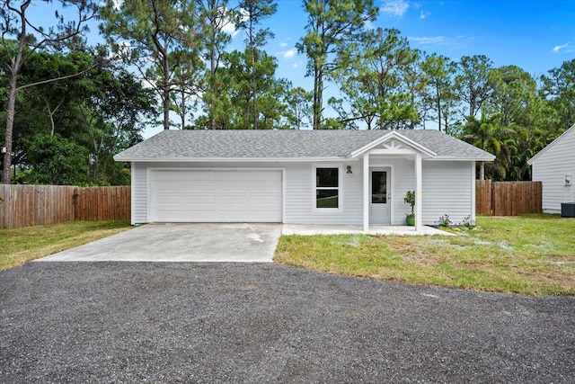 ranch-style home featuring a garage, fence, driveway, and a front lawn