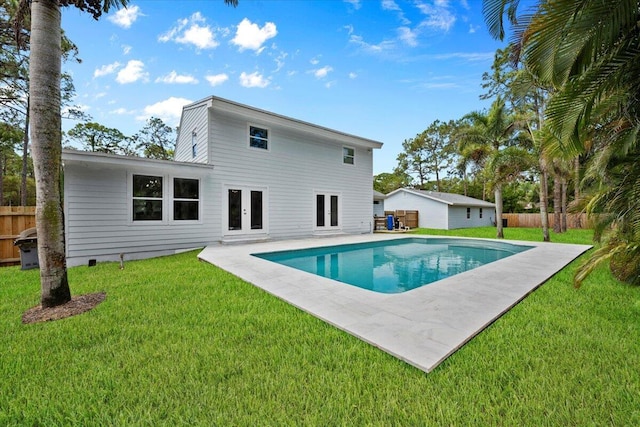 view of swimming pool featuring fence, french doors, a fenced in pool, a patio area, and a lawn