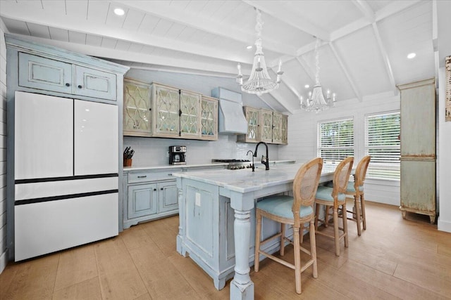 kitchen featuring white refrigerator, light countertops, lofted ceiling with beams, a notable chandelier, and custom range hood