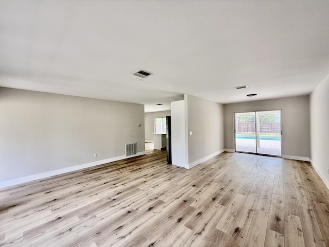 unfurnished living room featuring visible vents, a wealth of natural light, and light wood-type flooring