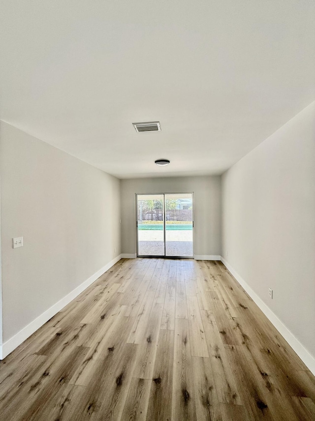 spare room featuring visible vents, light wood finished floors, and baseboards