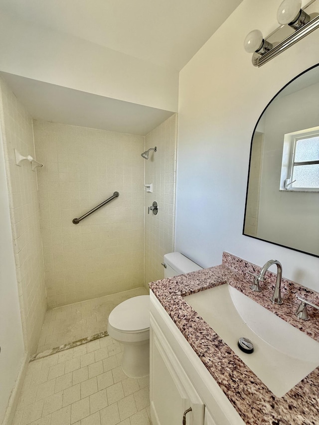 bathroom with vanity, tile patterned floors, a tile shower, and toilet