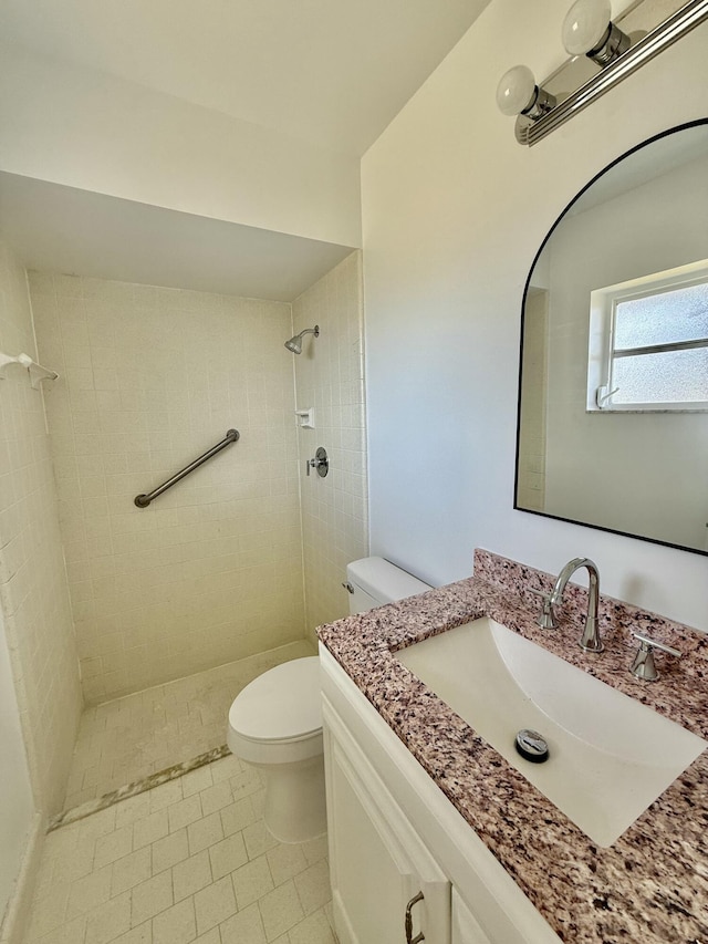 bathroom with vanity, tile patterned floors, toilet, and tiled shower