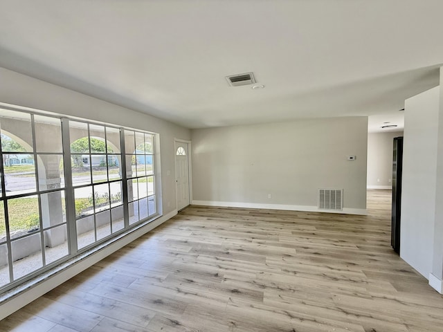 spare room featuring baseboards, visible vents, and light wood-style floors