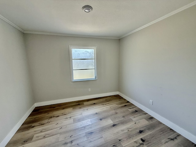 empty room featuring baseboards, ornamental molding, and wood finished floors