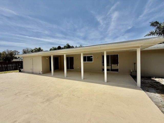 rear view of house with fence, a patio, and stucco siding