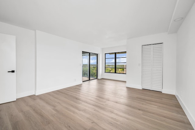unfurnished bedroom with baseboards, light wood-style flooring, and access to exterior