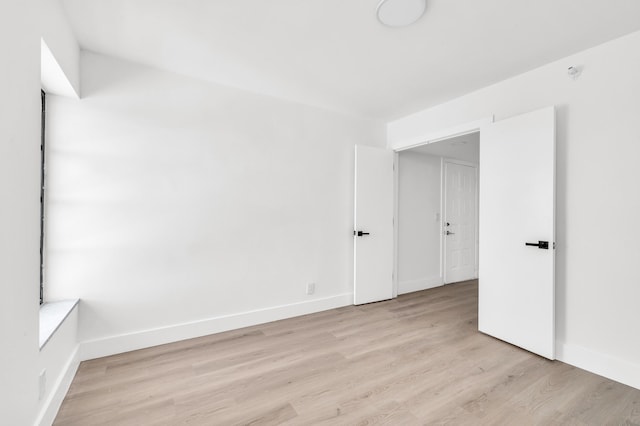 empty room featuring baseboards and light wood finished floors