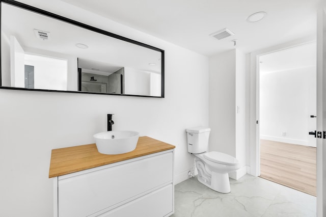 bathroom featuring vanity, toilet, marble finish floor, baseboards, and visible vents