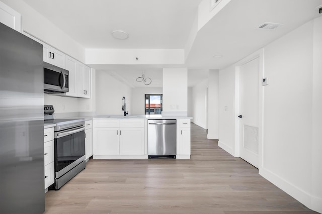 kitchen featuring visible vents, appliances with stainless steel finishes, a sink, light countertops, and light wood-style floors