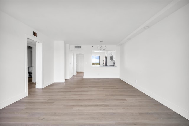 unfurnished living room featuring baseboards, visible vents, and light wood-style floors