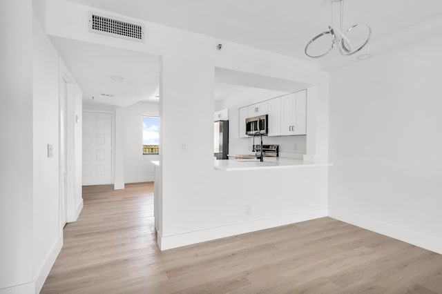 kitchen featuring white cabinets, appliances with stainless steel finishes, light wood finished floors, and visible vents