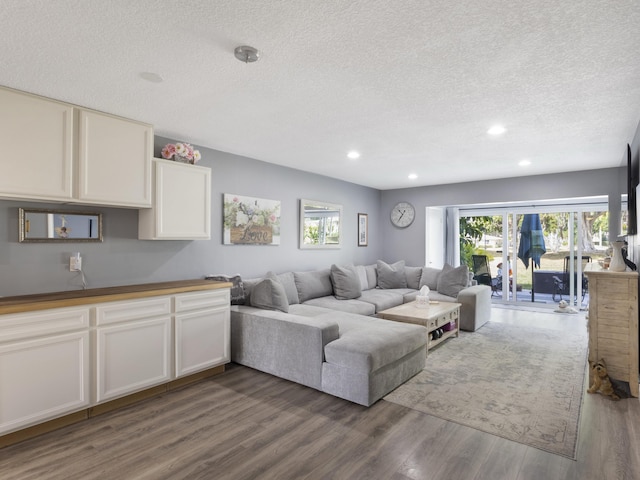 living room with recessed lighting, a textured ceiling, and wood finished floors