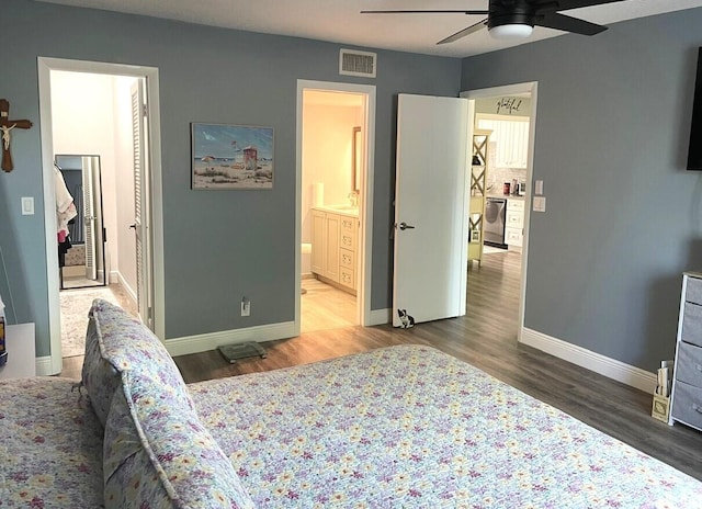 bedroom with baseboards, visible vents, wood finished floors, and ensuite bathroom
