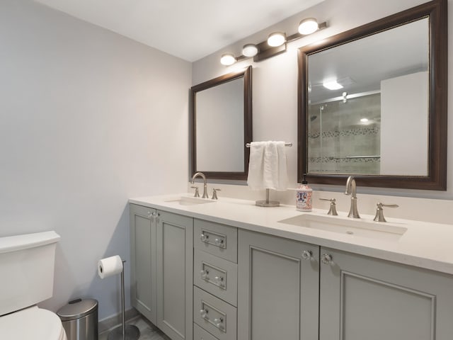 full bath with double vanity, toilet, a sink, and a stall shower