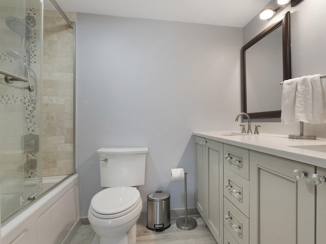 full bath with toilet, baseboards, combined bath / shower with glass door, and vanity