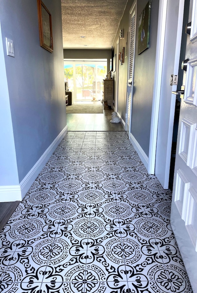 corridor with baseboards and a textured ceiling