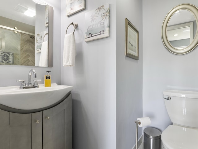 bathroom featuring vanity, a shower with shower door, and toilet