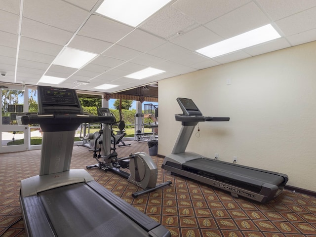 workout area featuring carpet floors, baseboards, and a paneled ceiling