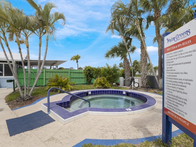 view of swimming pool featuring a community hot tub and fence