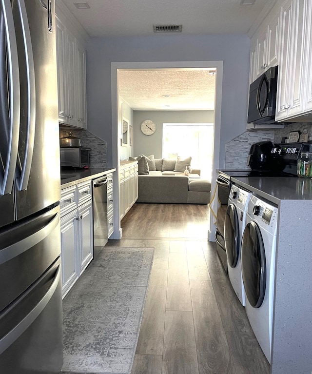 kitchen with backsplash, visible vents, appliances with stainless steel finishes, dark wood-style floors, and washer and dryer