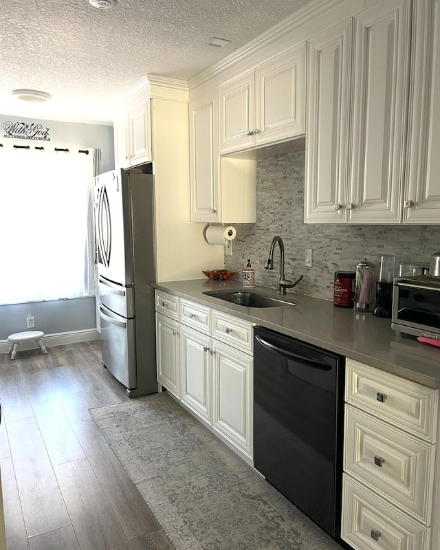 kitchen featuring freestanding refrigerator, a textured ceiling, a sink, light wood finished floors, and dishwasher