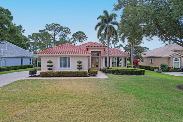 mediterranean / spanish-style house featuring french doors, a tile roof, a front yard, and stucco siding