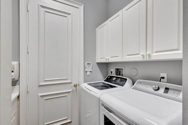clothes washing area featuring washer and dryer and cabinet space