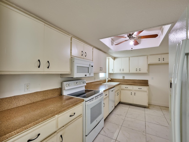 kitchen featuring marble finish floor, white appliances, ceiling fan, a sink, and a skylight