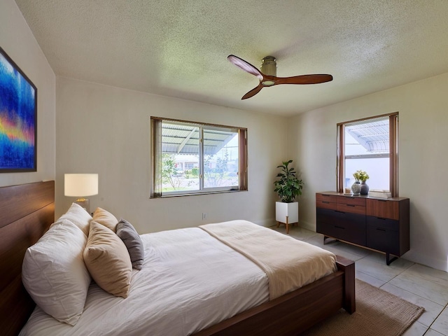 bedroom featuring light tile patterned floors, multiple windows, and a textured ceiling