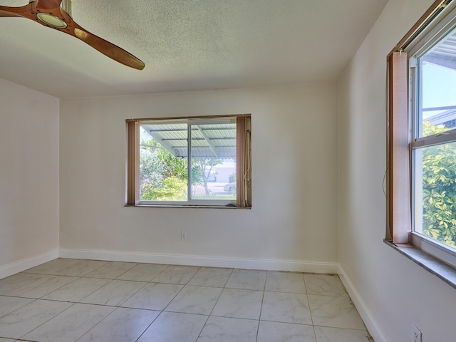 spare room featuring a textured ceiling, baseboards, and marble finish floor